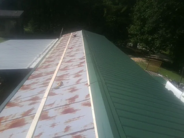 Old rusted panels beside newly installed green metal roofing — Wind Damage Roof Repair by Roofing Brothers in Kiamesha Lake