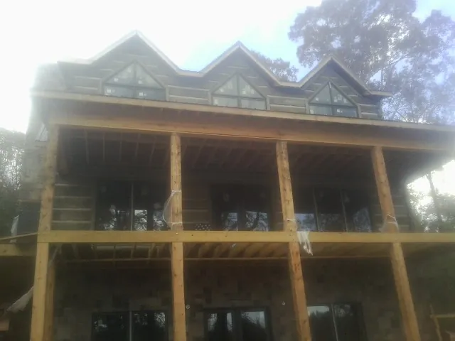 Dormers and porch framing on a large log home under construction — Roof Coating work by our crew in Kiamesha Lake