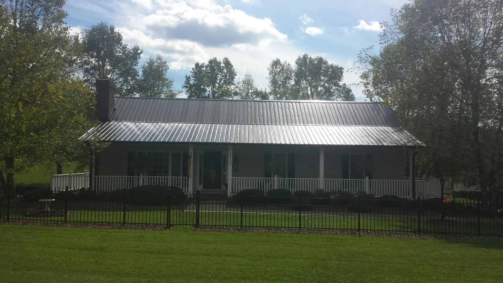 Gray metal roof on a brick ranch with a full width front porch — Gutter Guard Installation work by our crew in Kiamesha Lake