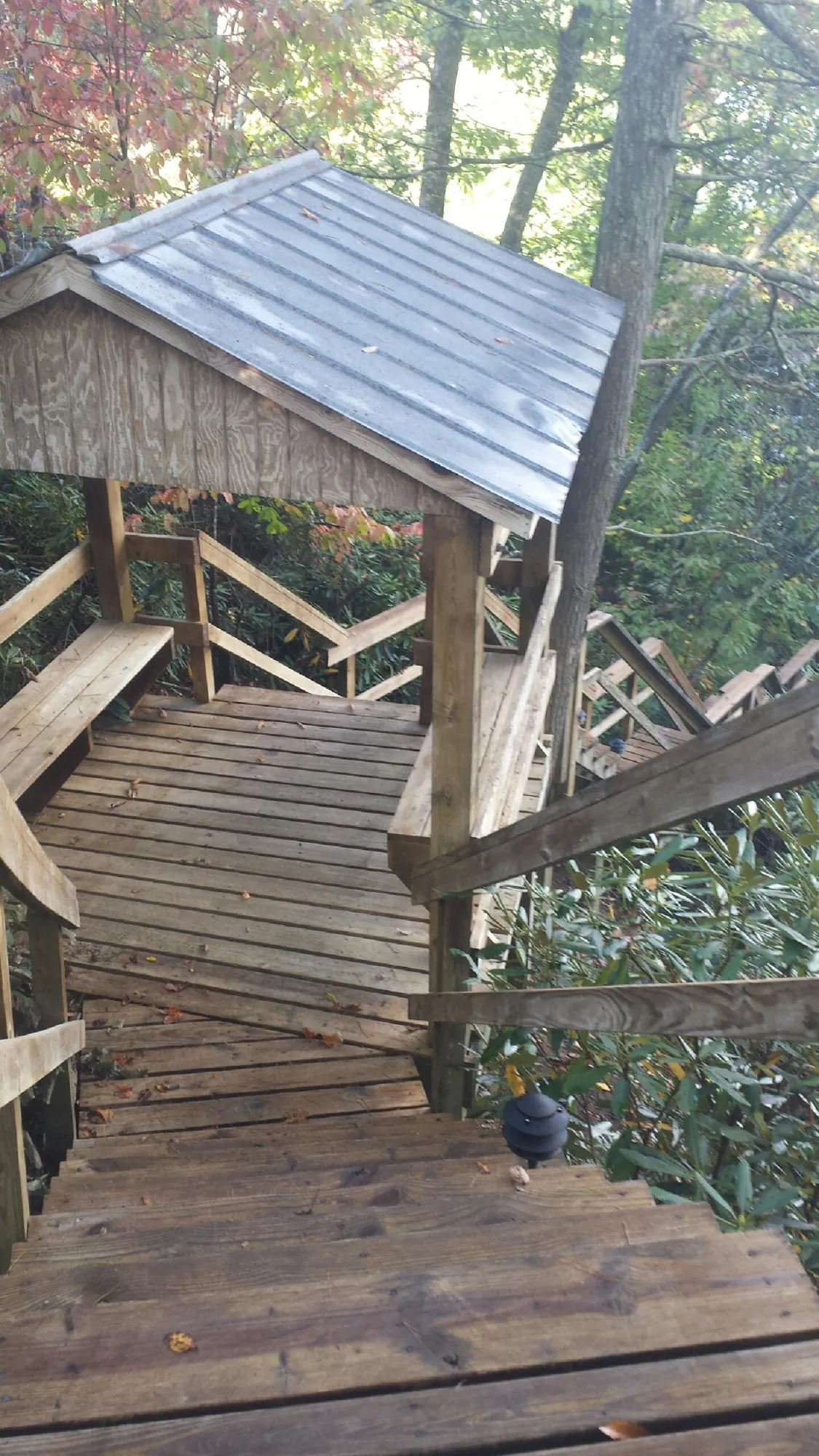 Metal roofed shelter over wooden steps on a wooded walkway — Skylight Repair & Installation work by our crew in Kiamesha Lake