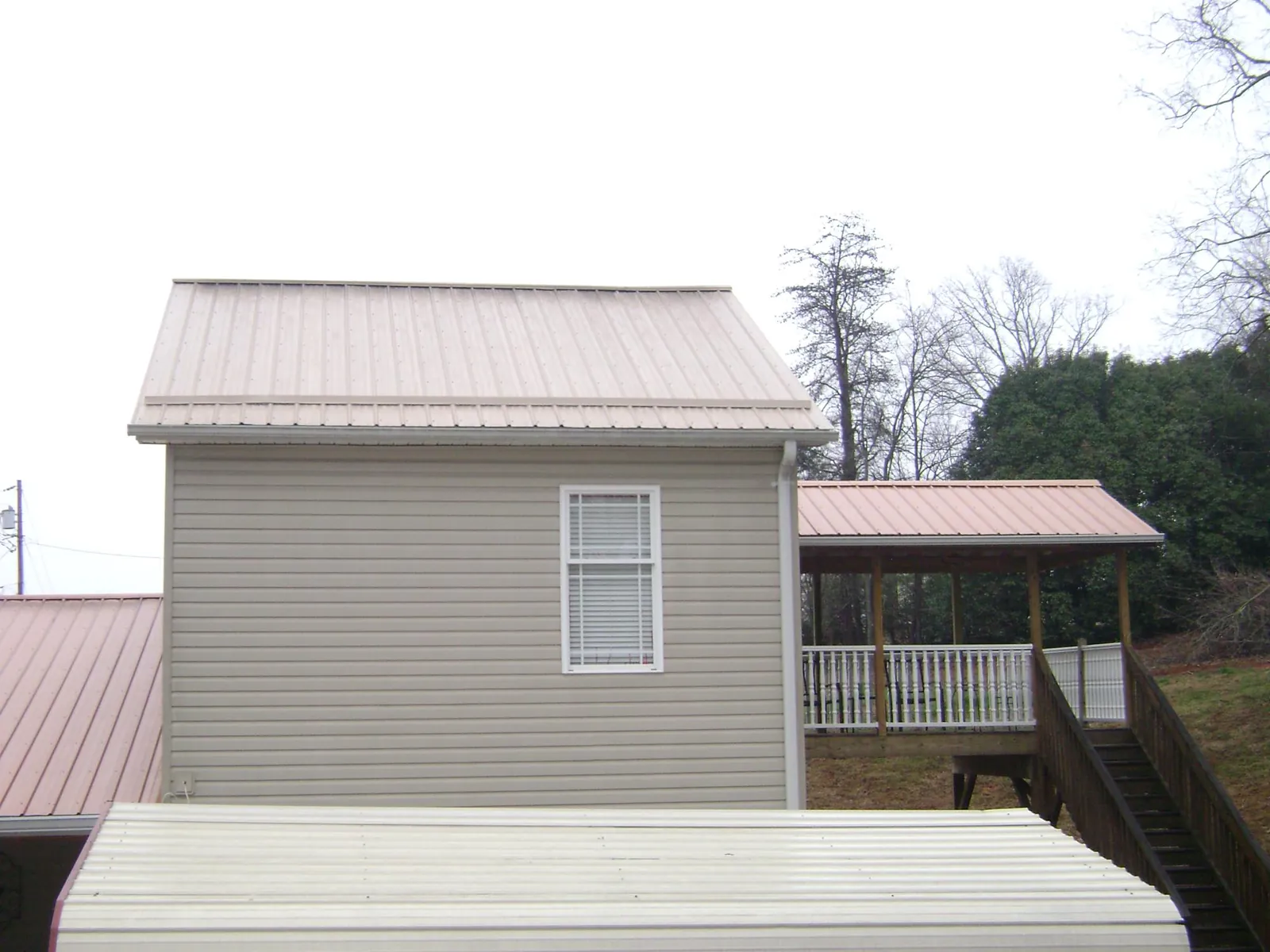 Tan metal roofs on a two story addition and attached porch, from a Roof Replacement job in Kiamesha Lake
