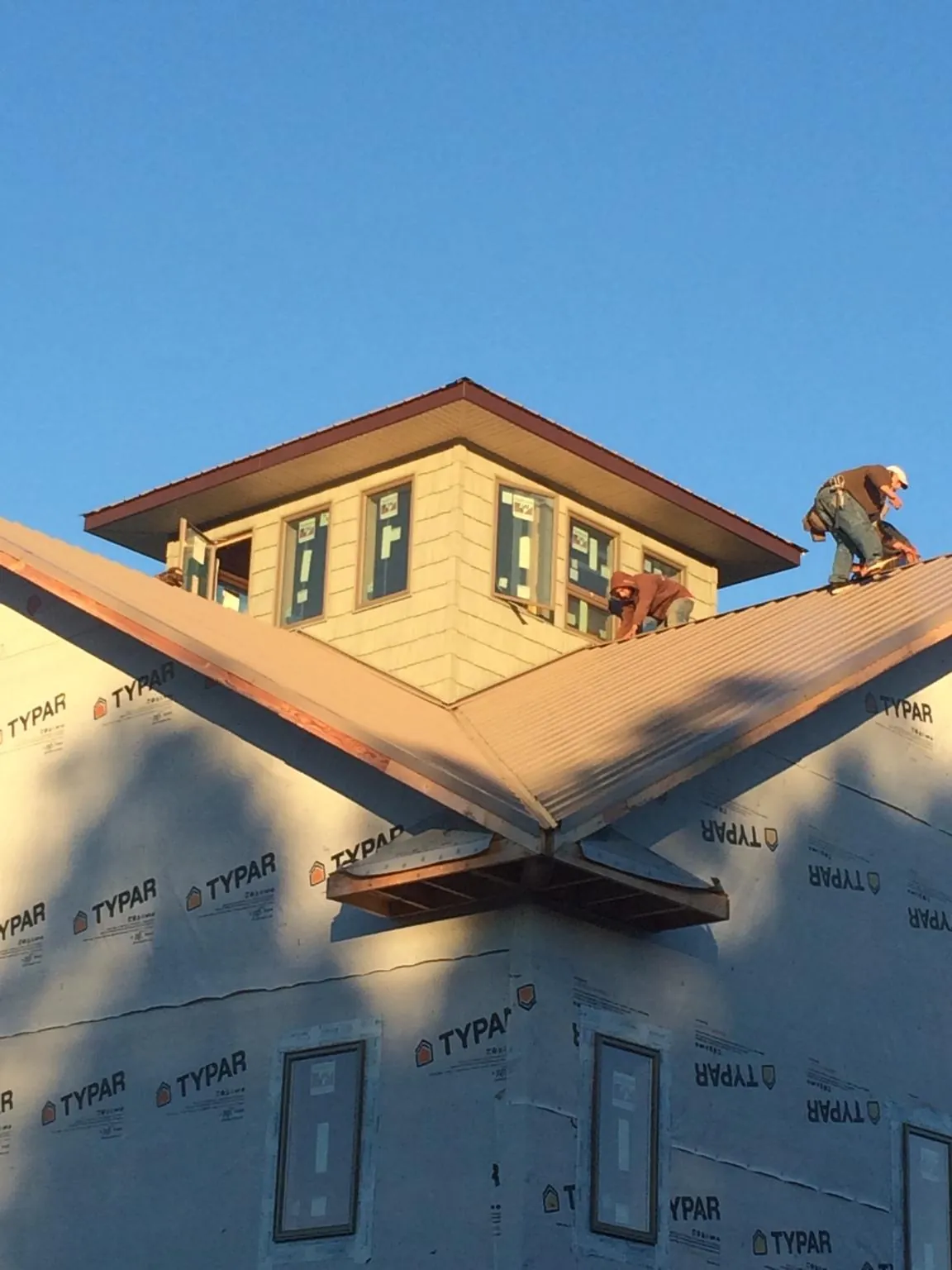 Roofers working around a rooftop cupola on a new metal roof at sunset — Roof Waterproofing in Kiamesha Lake by Roofing Brothers
